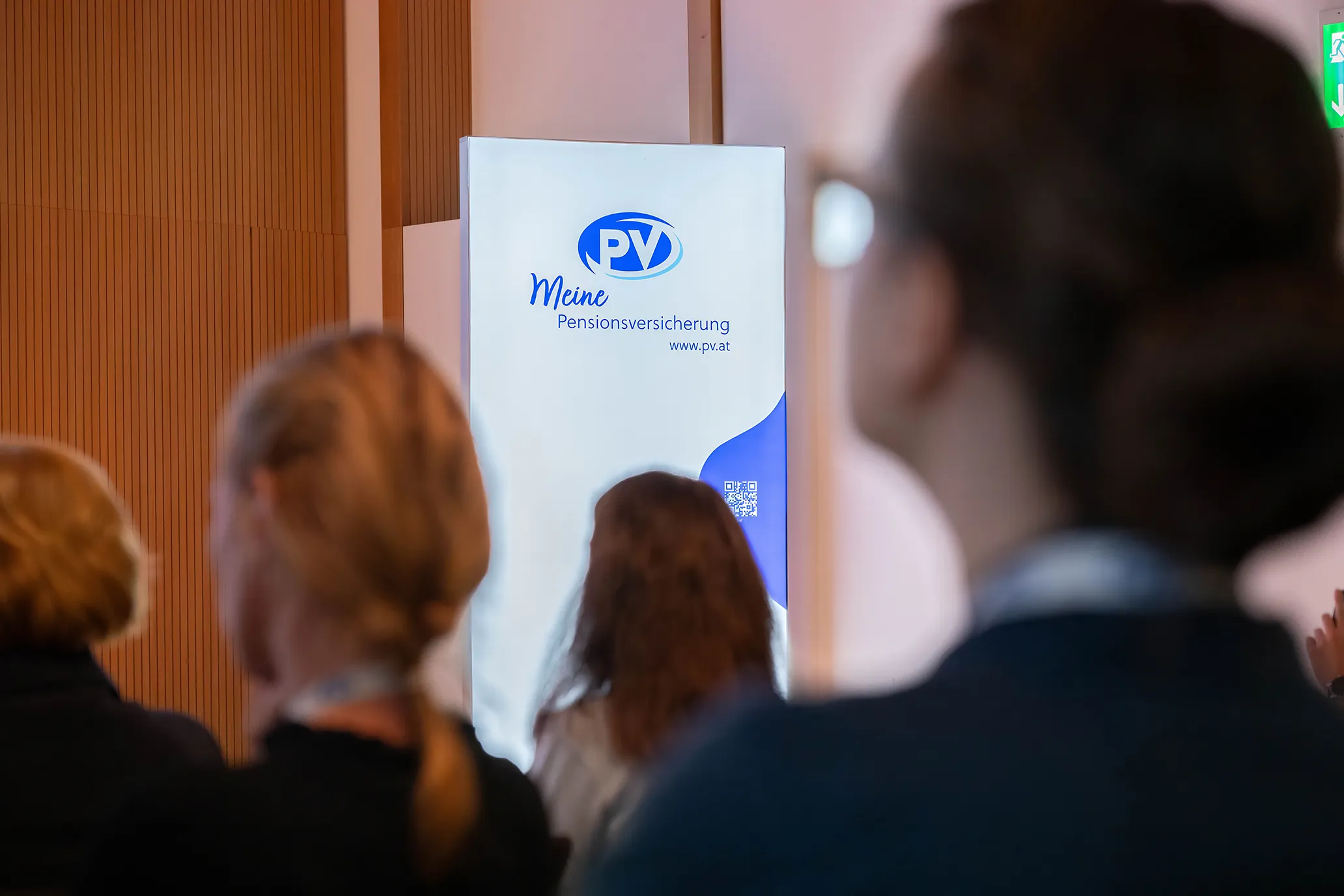 Leuchtwand Logo Pensionsversicherung Österreich vor Publikum