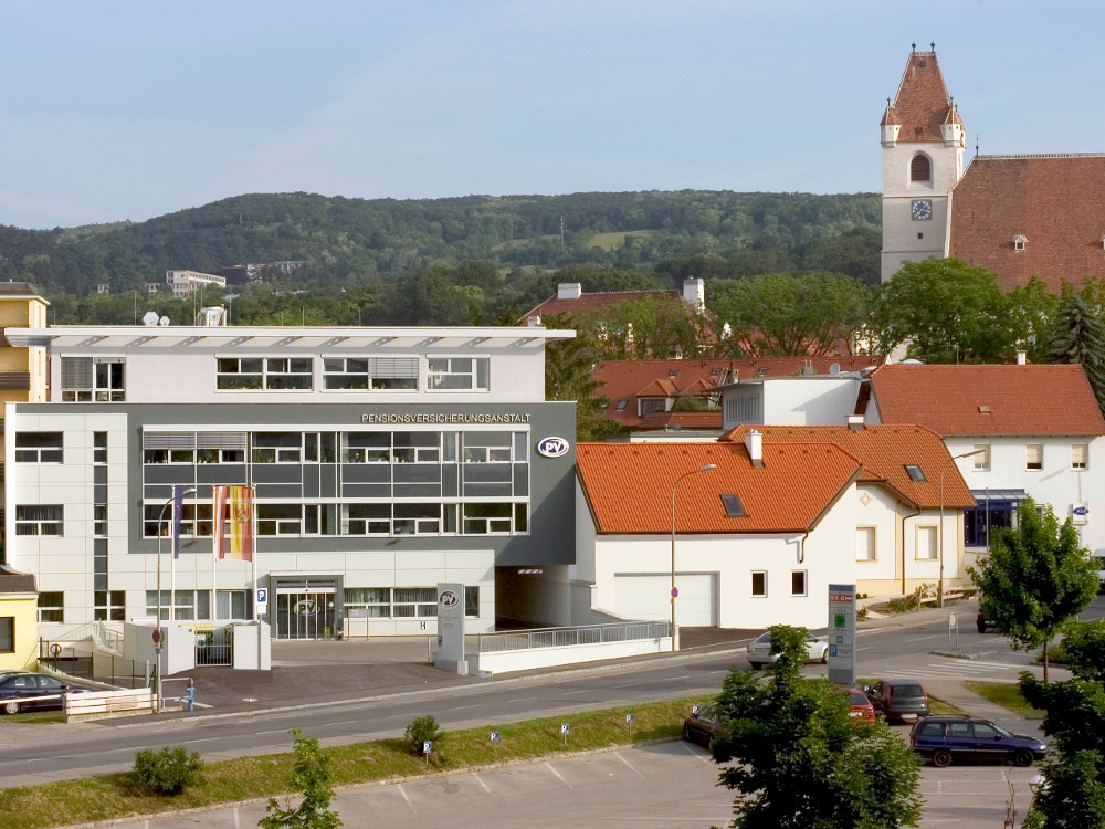 Außenansicht der Landesstelle Burgenland mit Glasfassade und Kirche im Hintergrund