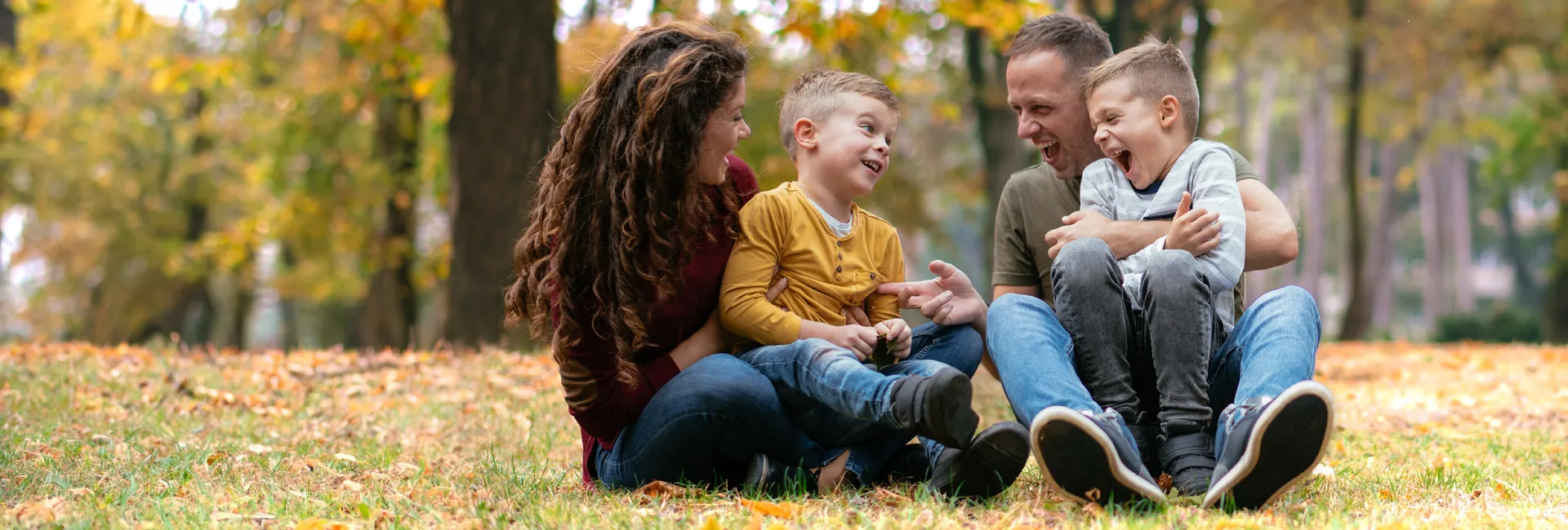 Pension und Familie: Mutter und Vater spielen mit zwei kleinen Kindern auf einer herbstlichen Wiese