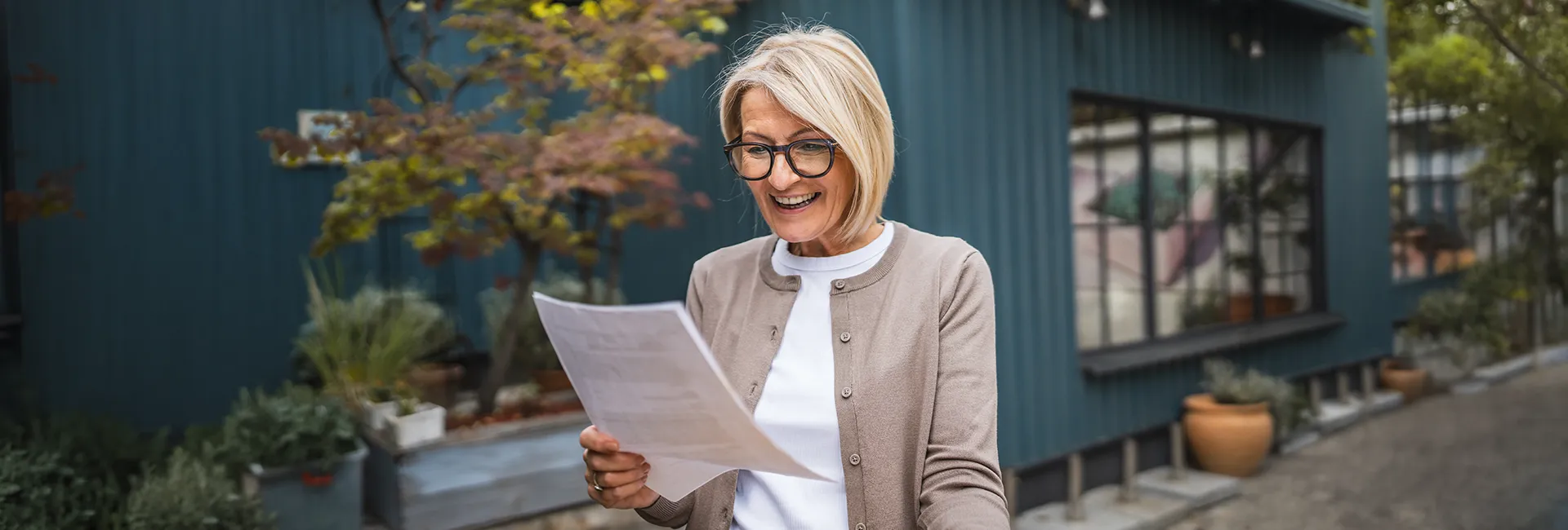 Pensionistin h&auml;lt Pensionszahlungsbeleg in der Hand und freut sich &uuml;ber die Sonderzahlung zur Pension